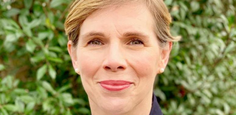 Headshot of woman with short haircut wearing pearls and navy sweater